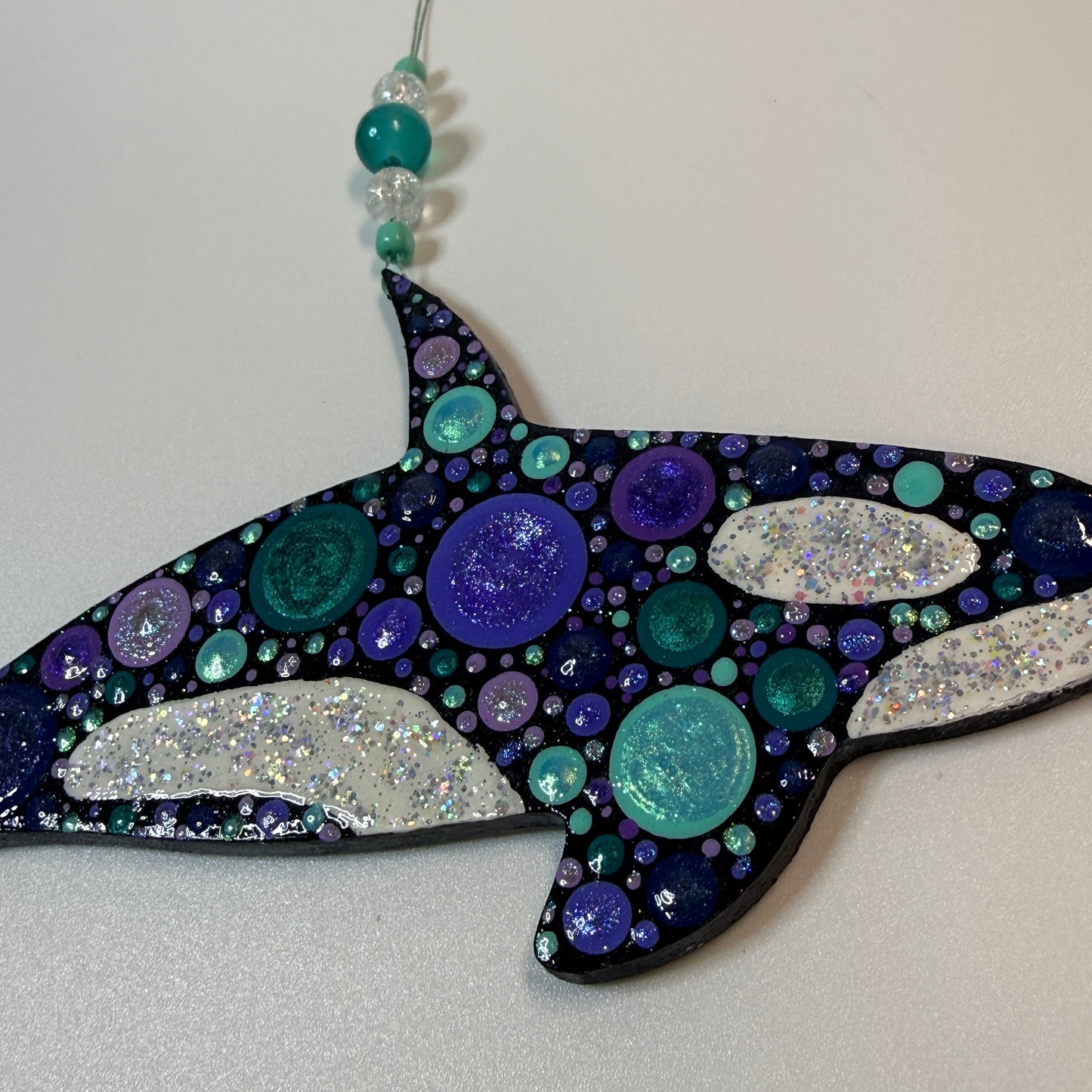 Decorative whale-shaped ornament with colorful beads on a black background